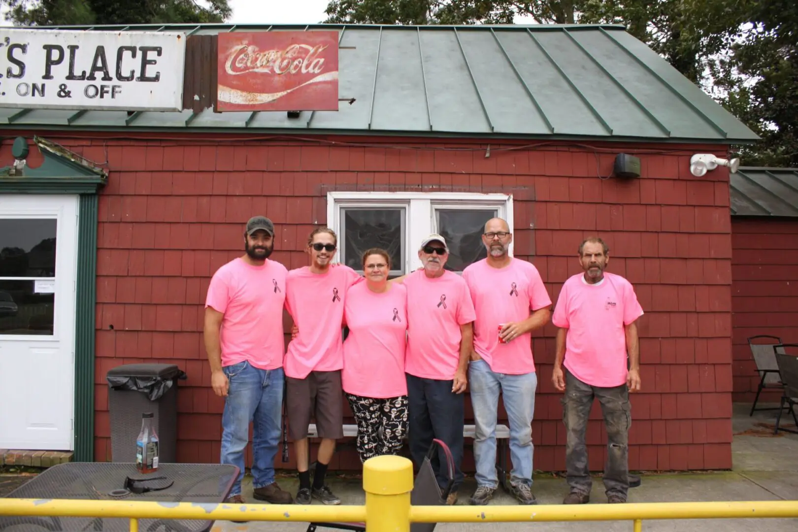 A group of people wearing pink shirts standing in front of a building.