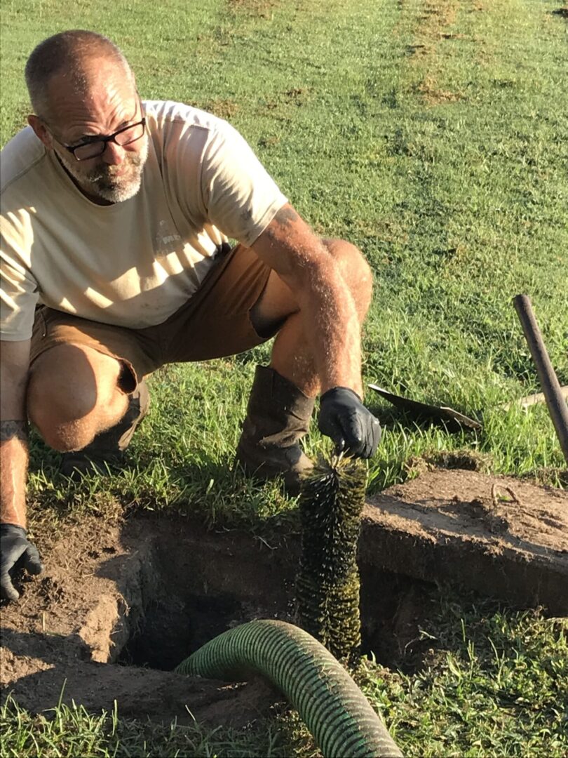 A man kneeling down next to a hole in the ground.