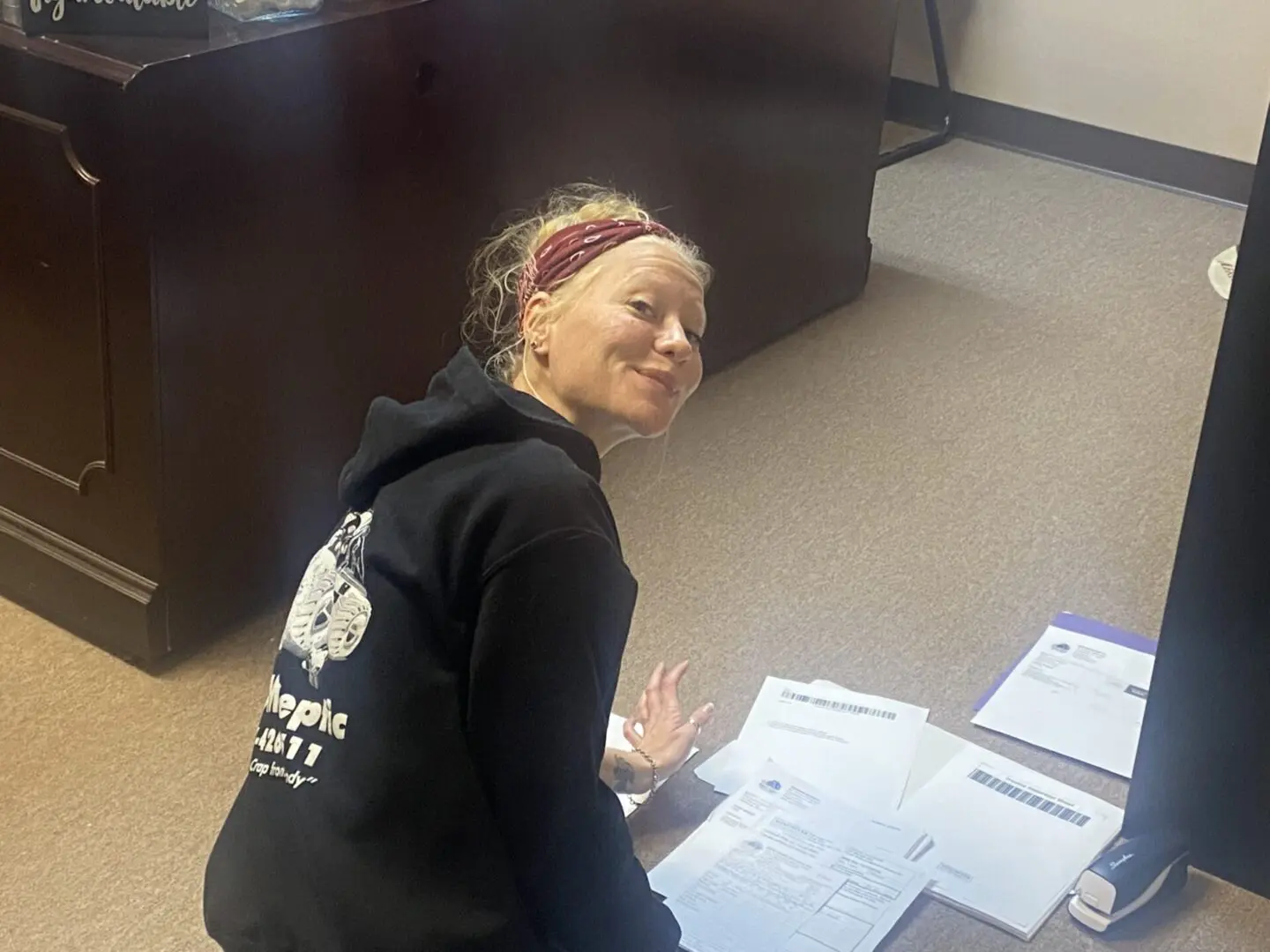 A woman sitting on the floor in front of papers.