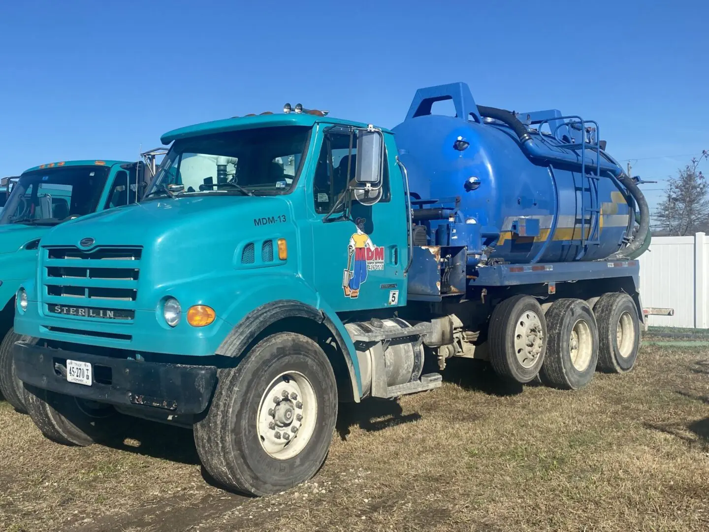 A blue truck is parked in the dirt.