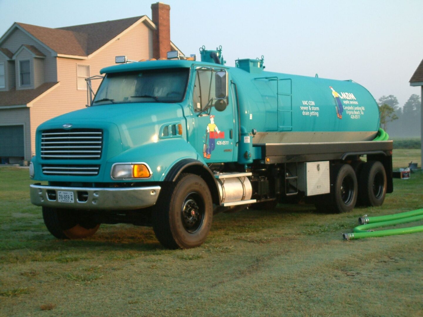 A blue truck parked in the grass near a house.