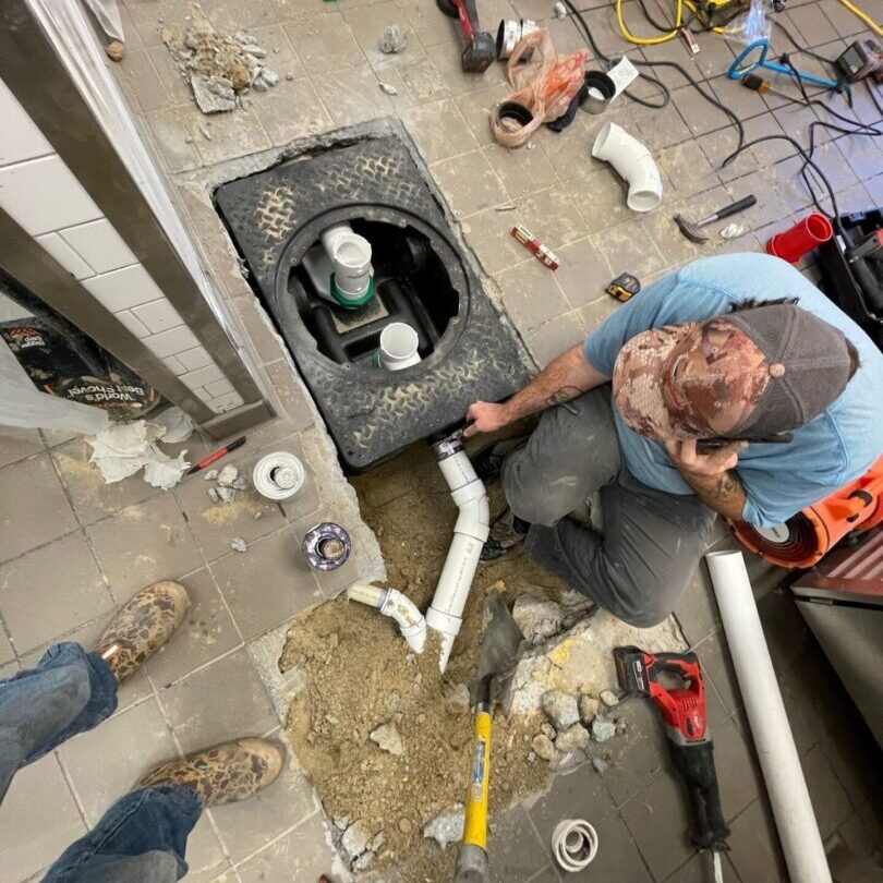 A man working on the floor of an unfinished room.